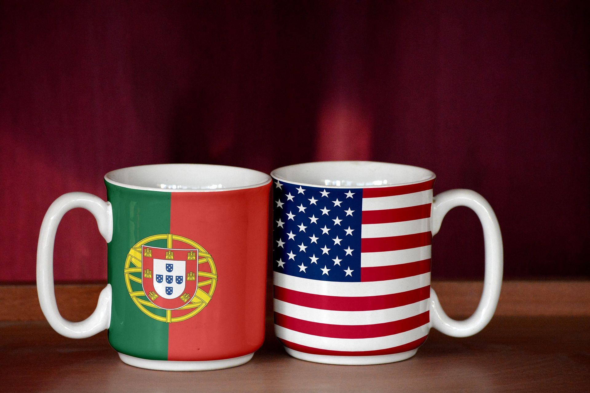 USA and Portugal flag on two cups with blurry background